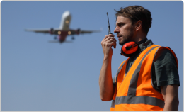 Airport Security Manager talking on a radio as a plane takes off.